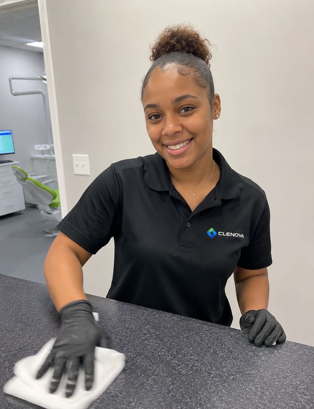 Clenova cleaning staff member smiling in a black polo shirt with logo.
