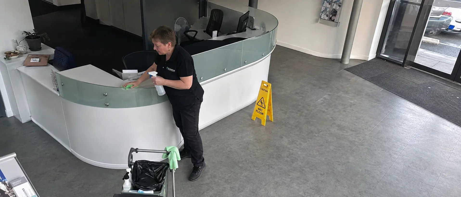 Commercial cleaner sanitising office reception desk - Illustrative Image