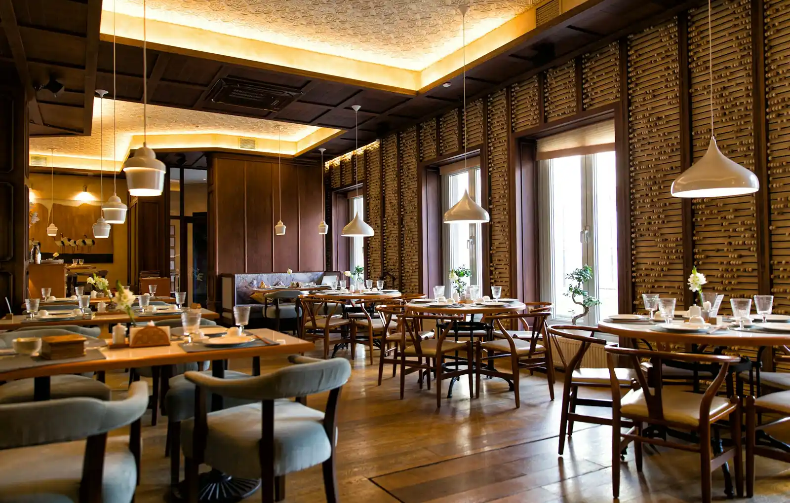 Clean restaurant interior with neatly arranged tables, chairs, pendant lighting and a tidy dining area.