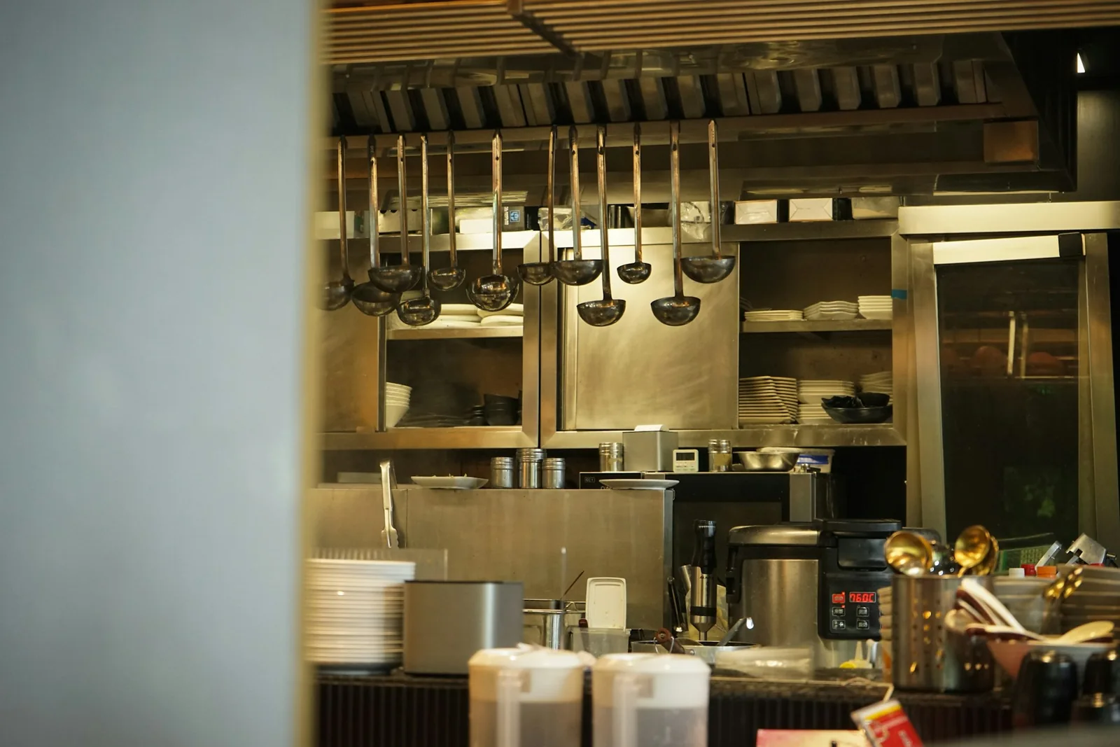 Clean commercial restaurant kitchen with stainless steel cooking equipment, utensils and preparation areas.